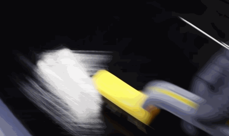 A heat gun is applied to a glossy black car panel to smooth out paint protection film during installation. The film reacts to the heat for better adhesion.