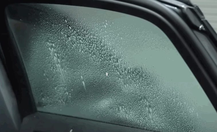 Car side window covered in water droplets before window tinting application.