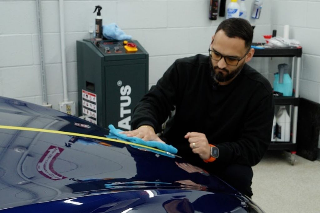 Prestige Auto Appearance expert polishing a car hood with a microfiber cloth to achieve a flawless, glossy finish.