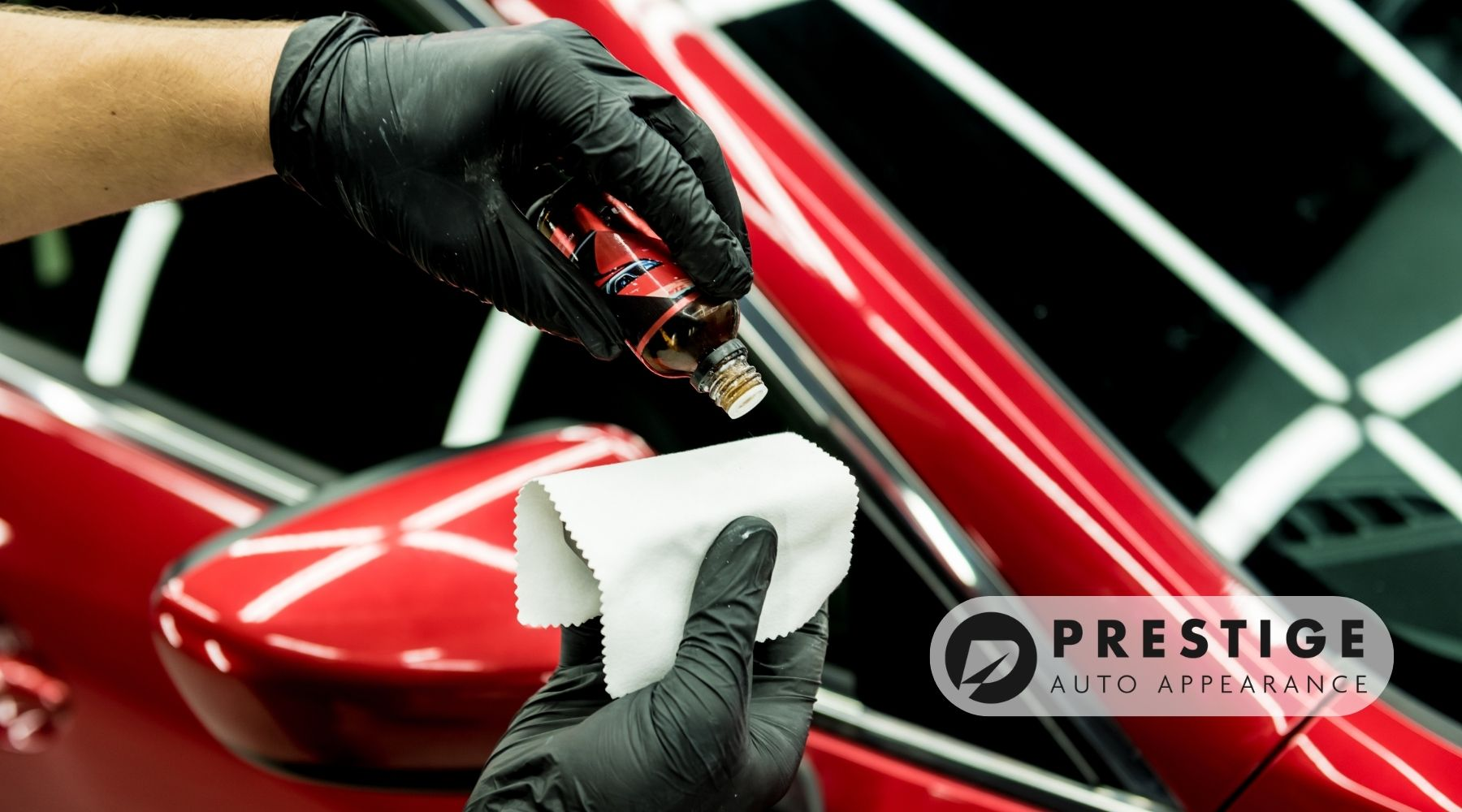 Technician applying ceramic coating to a red car using a microfiber cloth