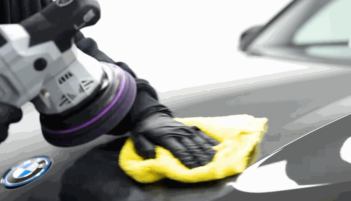 Detailer hand-buffs a BMW’s hood after machine polishing