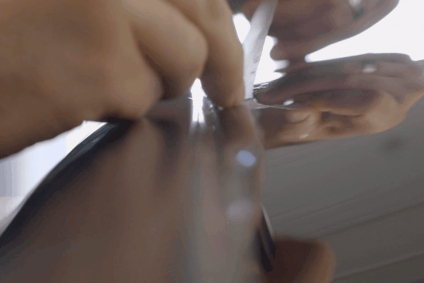 Professional carefully removing paint protection film (PPF) from a car surface.