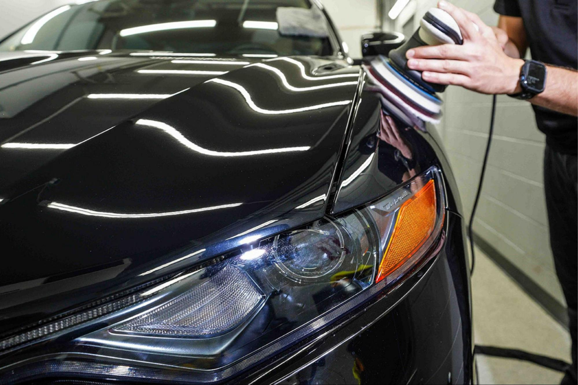 Prestige Auto Appearance technician polishing the hood of a black car to achieve a flawless, glossy finish.