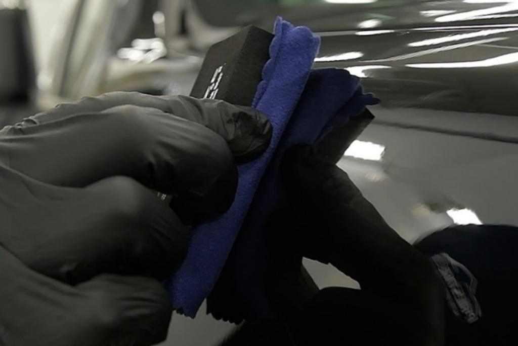 Close-up of ceramic coating being applied to a car’s paint surface.