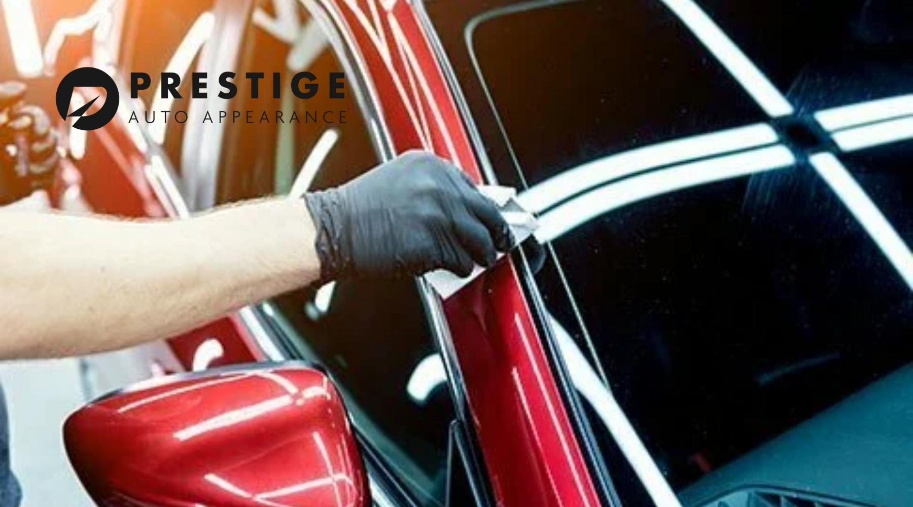 Technician applying ceramic coating to a red vehicle at Prestige Auto Appearance.