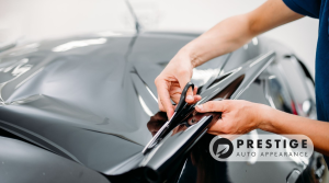 Technician applying black vinyl wrap to a car hood at Prestige Auto Appearance in Allentown, PA.