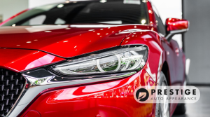 Close-up of a red car with glossy paint and polished headlights after professional auto detailing by Prestige Auto Appearance.
