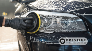 Technician polishing a car headlight during professional auto detailing at Prestige Auto Appearance in Lehigh Valley.