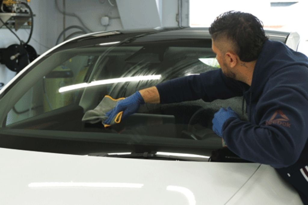 Auto detailing technician cleaning a vehicle windshield during professional car detailing service in Lehigh Valley.