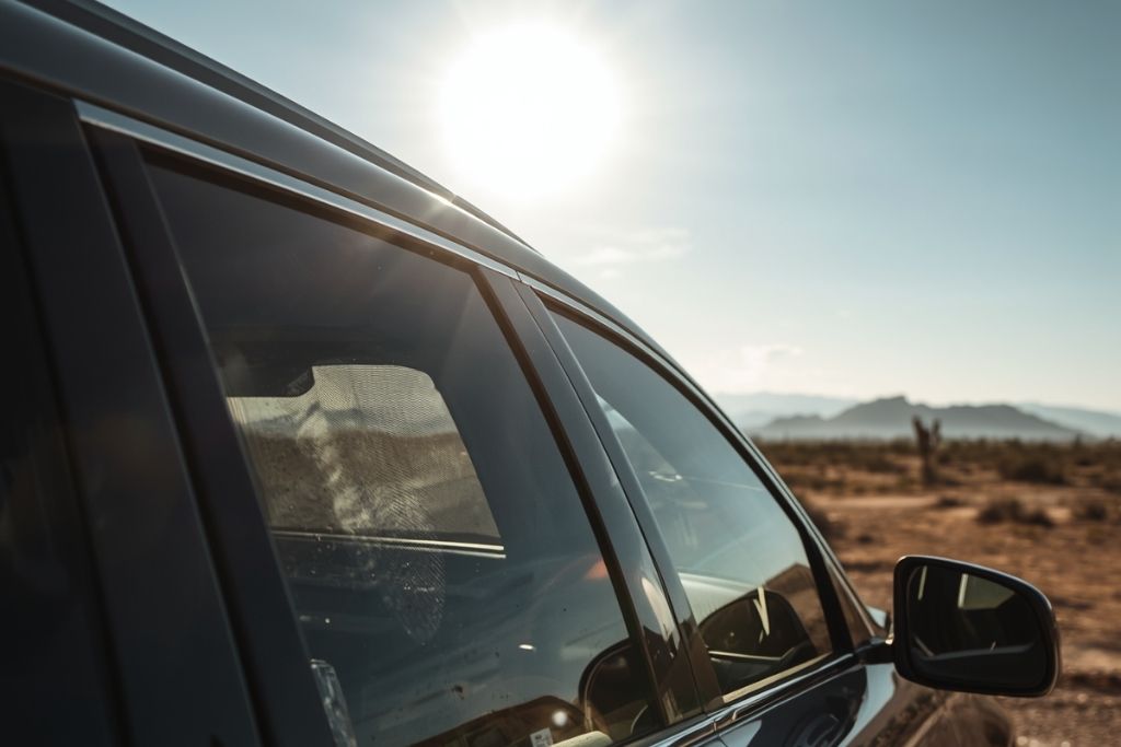 Car with tinted windows parked under bright summer sun, showing heat and glare protection.