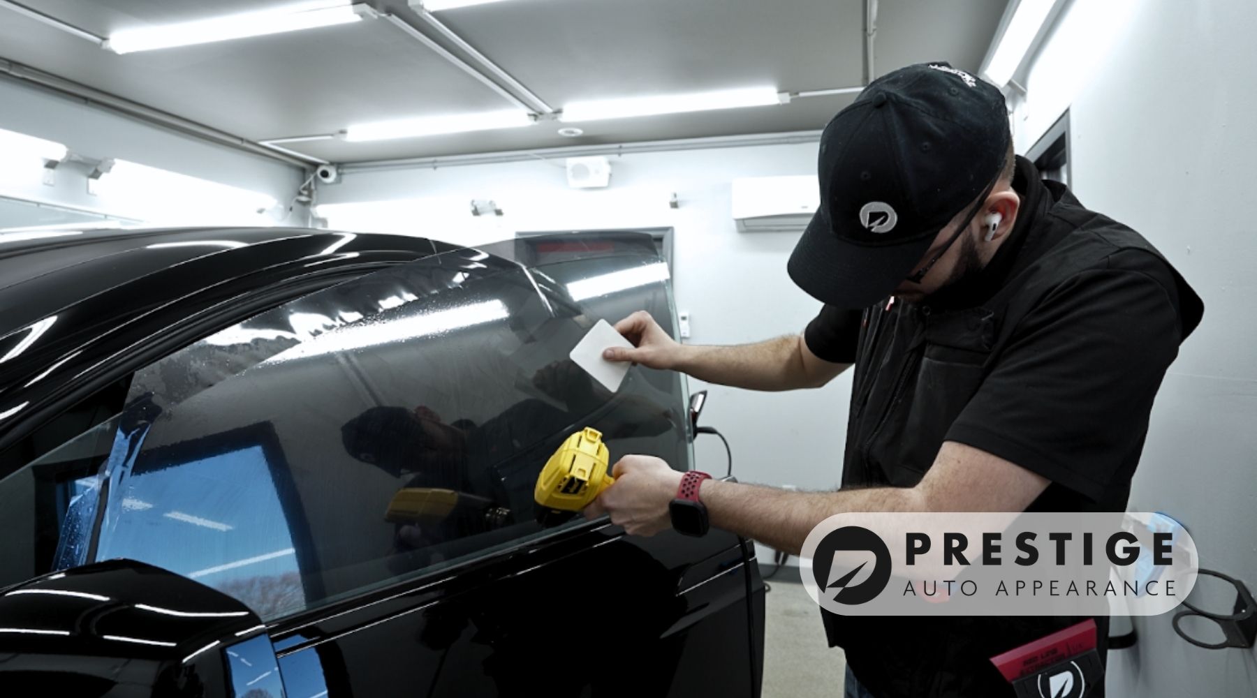 Technician at Prestige Auto Appearance professionally installing ceramic window tint on a vehicle in a clean Allentown auto detailing studio.