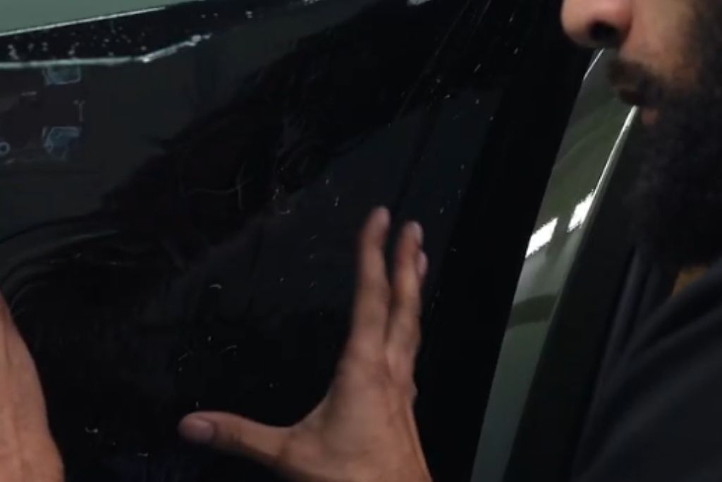 Close-up of a technician carefully applying automotive window tint film during a professional installation process.