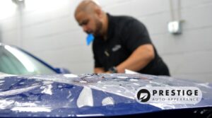 Prestige Auto Appearance technician applying paint protection film to a blue vehicle in an Allentown detailing studio.